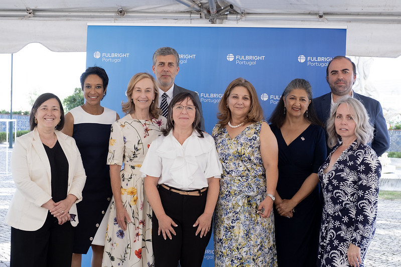 Sheree M. Mitchell standing with a group of people, smiling, in front of a Fulbright Portugal sign.