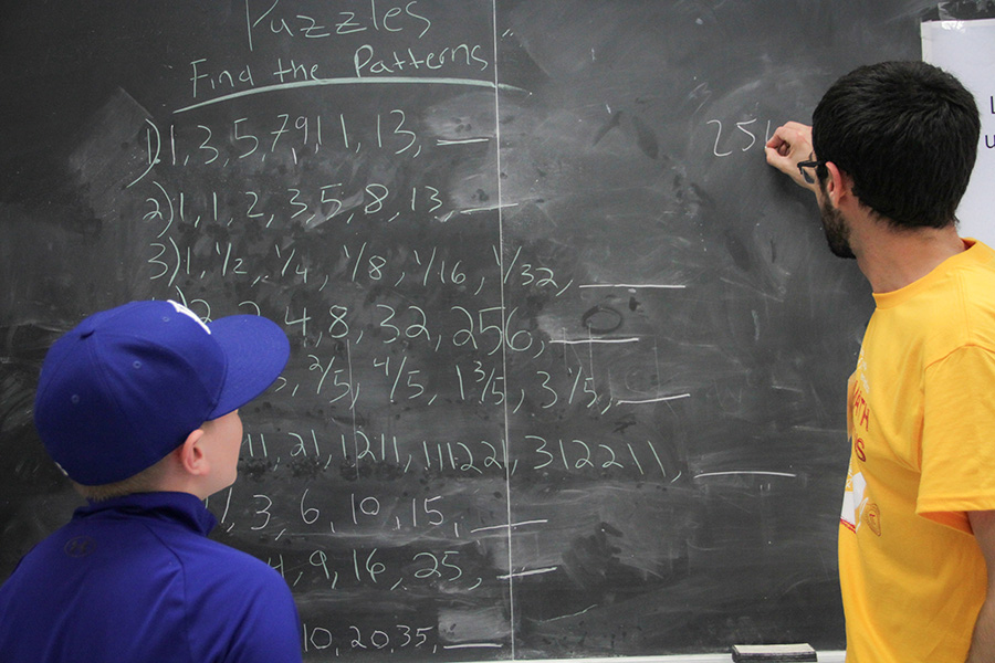 A volunteer and an attendee collaborate on a math puzzle. (Norah Sprott/College of Arts and Sciences)
