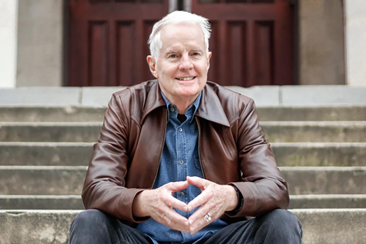 FSU professor David Kirby sits on a staircase outside with his hands folded.