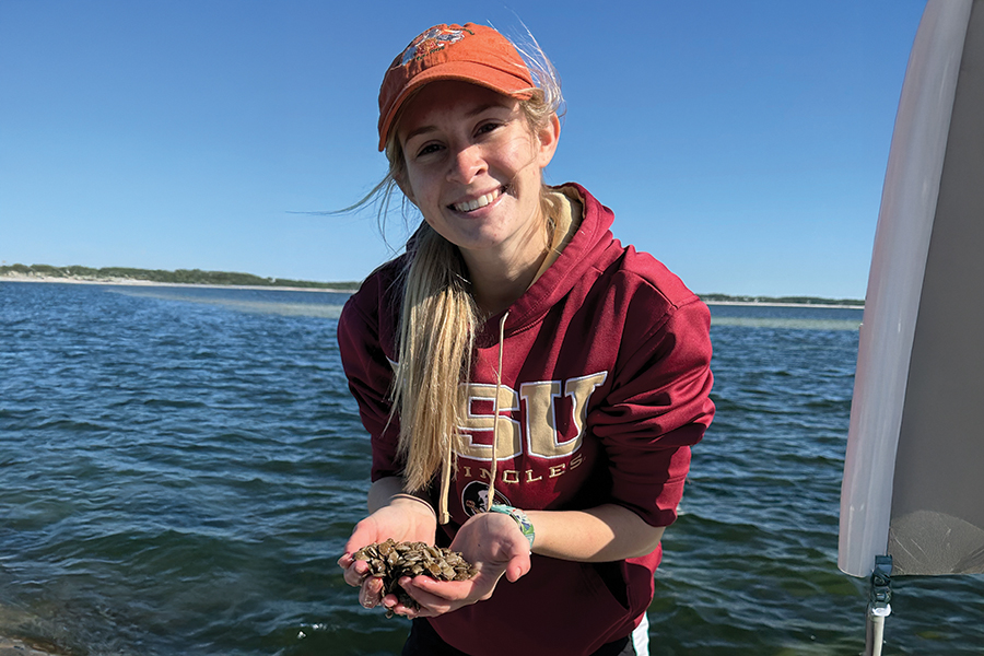 Morgan Hawkins holding juvenile scallops. Photo by Bailey Kilroy.