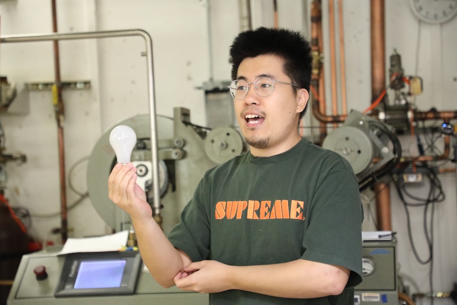 Physics doctoral student Haoyang Liu (pictured) demonstrates and discusses the continued research that increasingly optimizes the lightbulbs that illuminate our lives. Photo by Kendall Cooper.