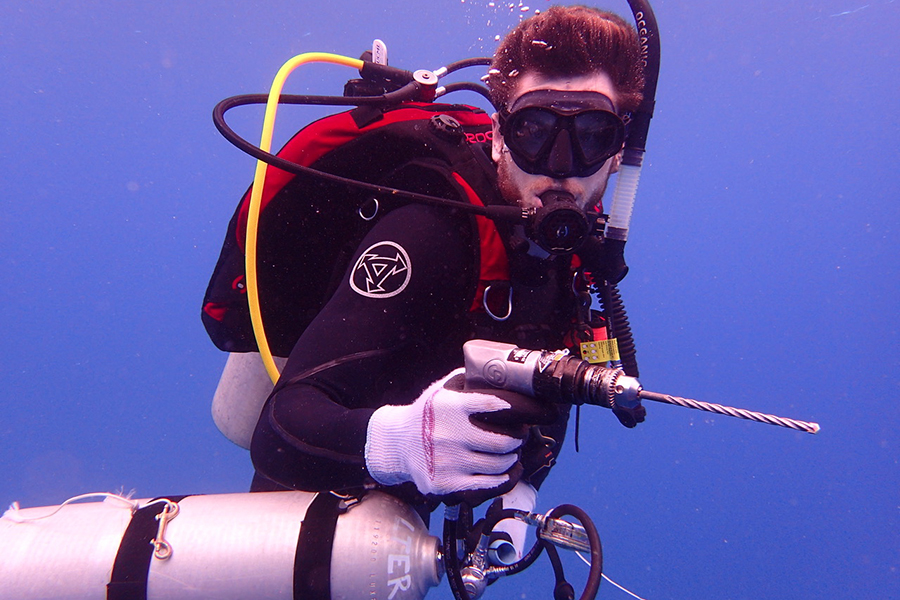 Diving Safety Officer Chris Peters ascends with a pneumatic drilling system during a project in Moorea, French Polynesia. Photo by Scott Burgess.