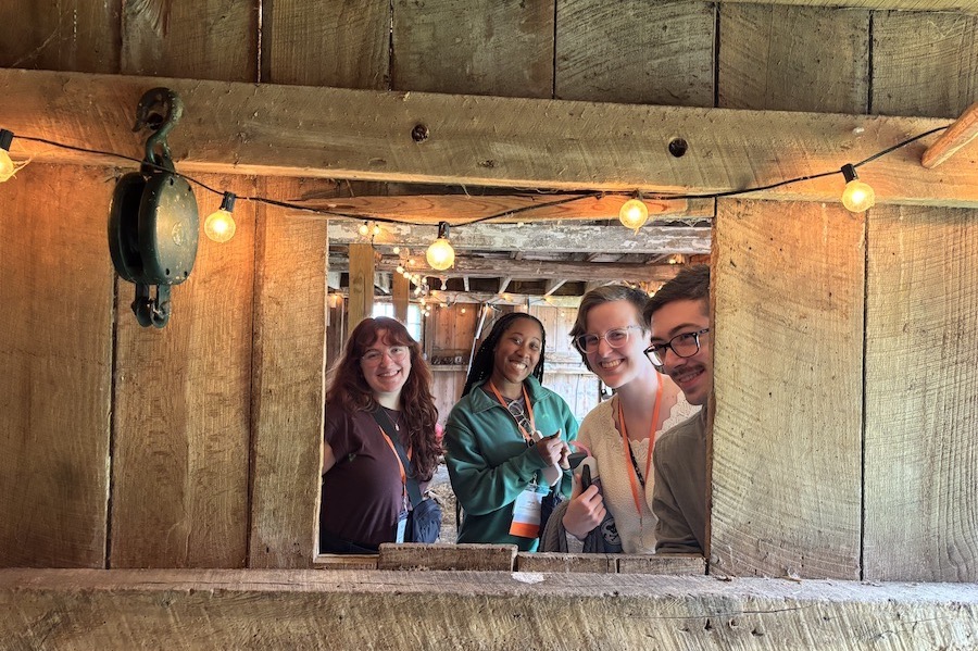 Camp, Cole, Evans, and MacKinlay look through a window in a historic wooden barn at Poplar Hall outside of Newark, Delaware. Photo by Conti.