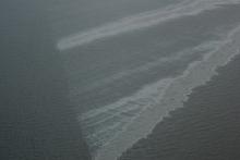 The Taylor Energy platform, about 10 miles off the coast of Louisiana, was destroyed by Hurricane Ivan in 2004 and started leaking oil immediately. Oil slicks, like this picture from 2013, were commonly seen over the site until a containment system was installed in 2019. (Courtesy of Ian MacDonald)