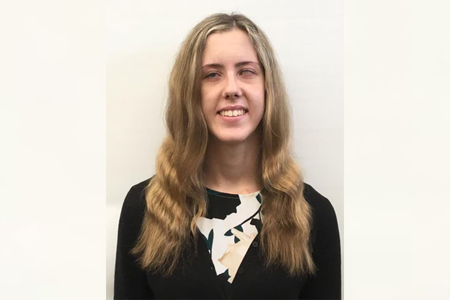 Neuroscience student and undergraduate researcher Gracie Delong in front of off-white background.