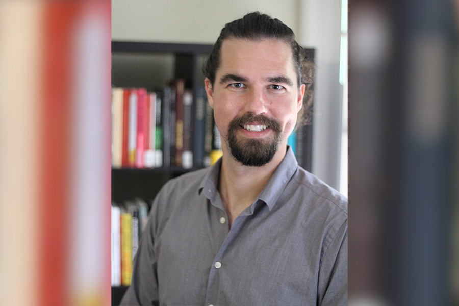 FSU postdoctoral researcher Sam Holley-Kline in front of a bookshelf