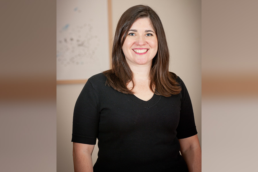 FSU alumna Melissa Rea smiling, wearing a black shirt and standing against a tan background.