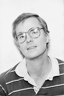 David Kirby in 1984 wearing glasses and a striped shirt.
