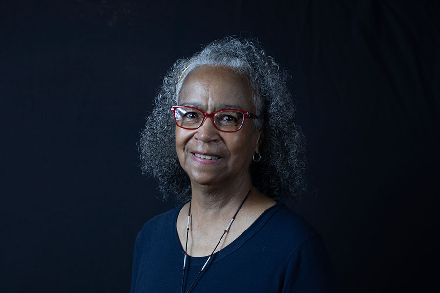 A photo of English professor Jerrilyn McGregory standing against a dark background.