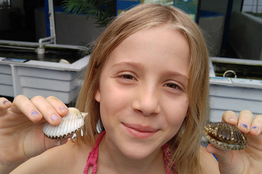 A child at Saturday-at-the-Sea poses with two scallops. Courtesy photo.